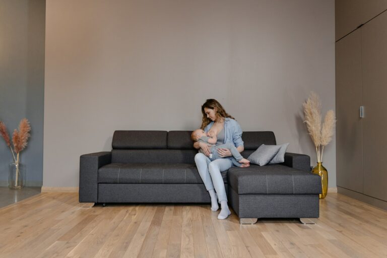 A Woman Sitting on the Couch while Breastfeeding Her Baby