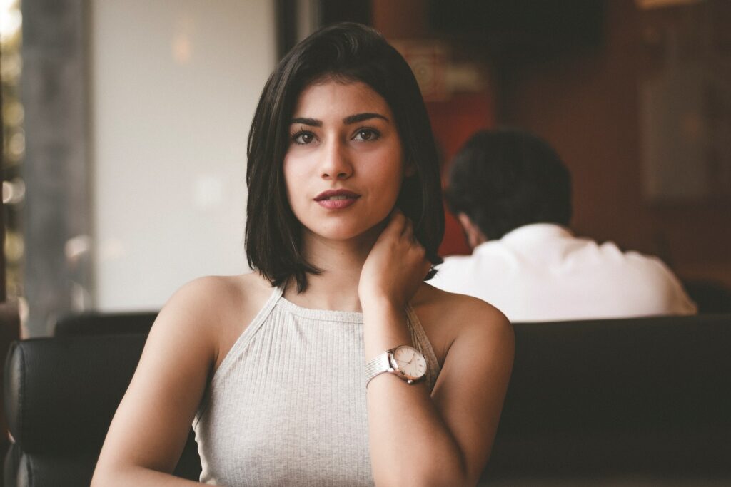 woman wearing gray spaghetti strap shirt sitting on black leather sofa close-up photo